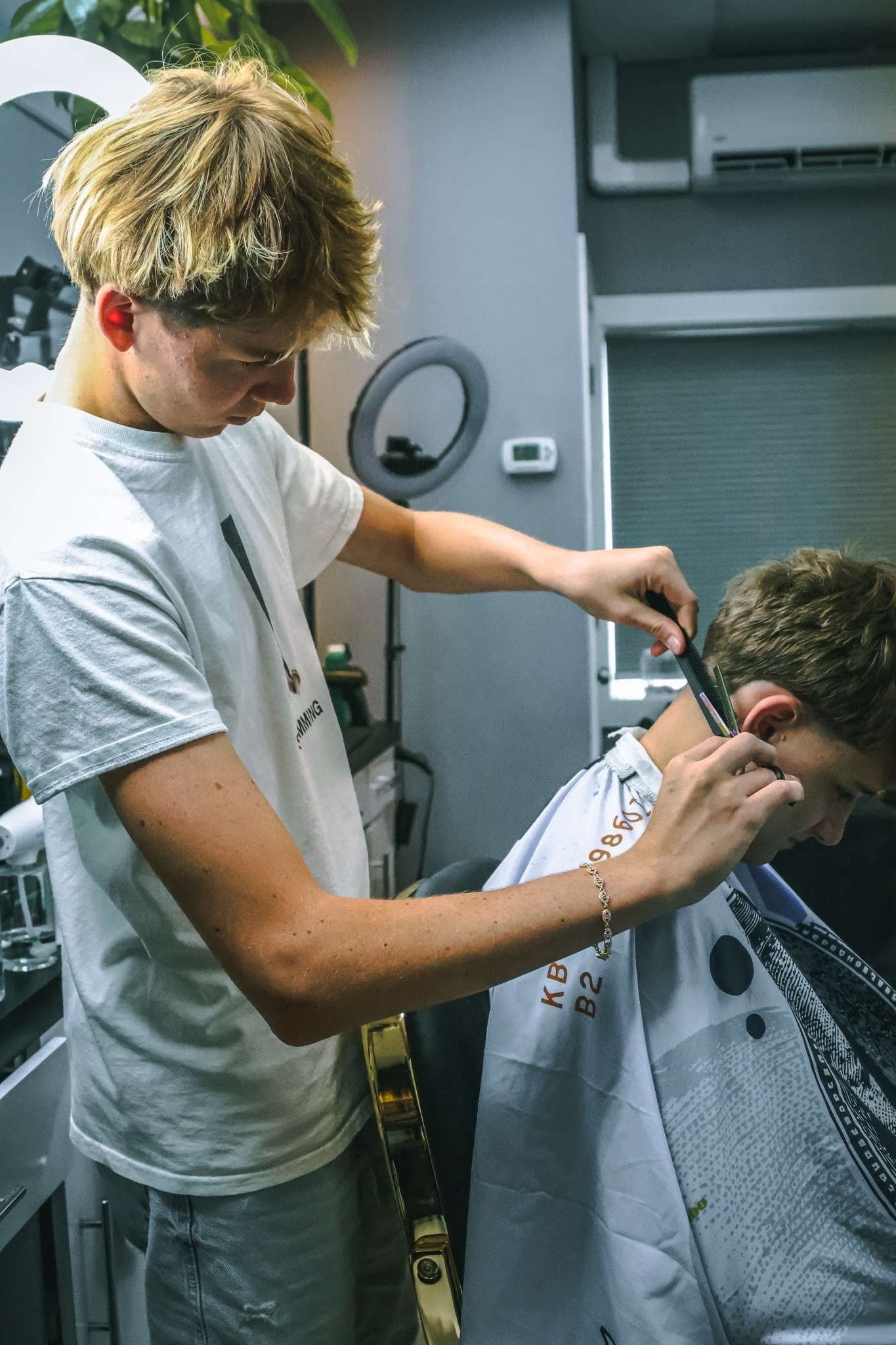 Wins focused mid-haircut in his studio, ring lights behind him